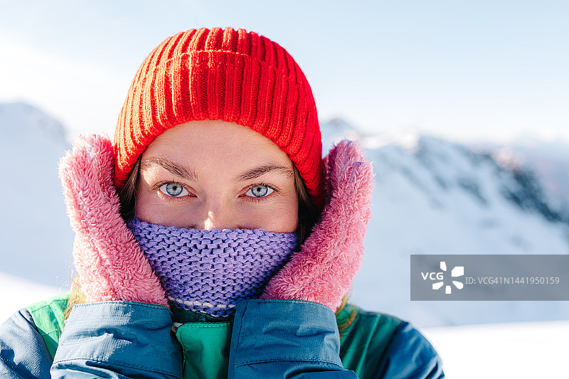 面带微笑的女人用围巾盖着脸走进了冬天的深山图片素材