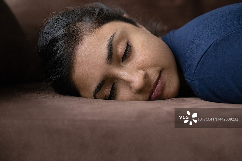 筋疲力尽的年轻印度女子睡在沙发上。图片素材