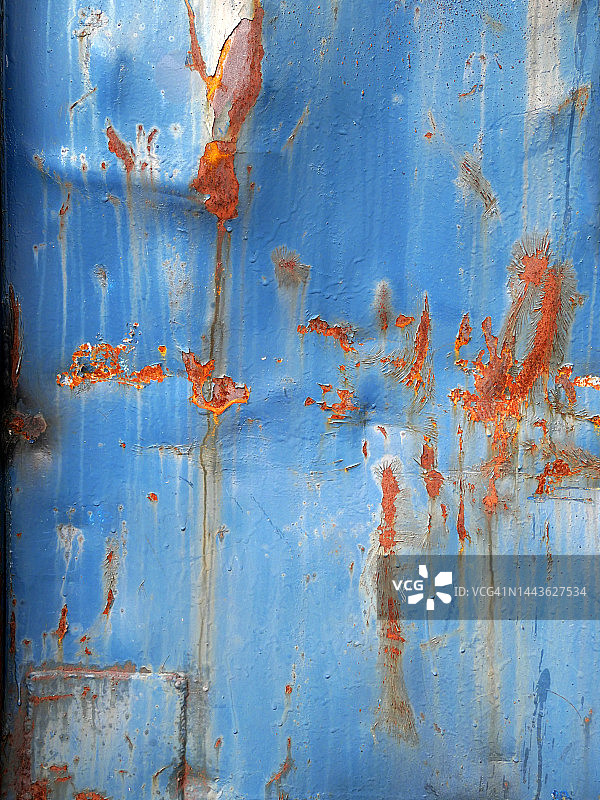 在巴黎，一块凹陷生锈的金属板上涂着风化的蓝色颜料图片素材
