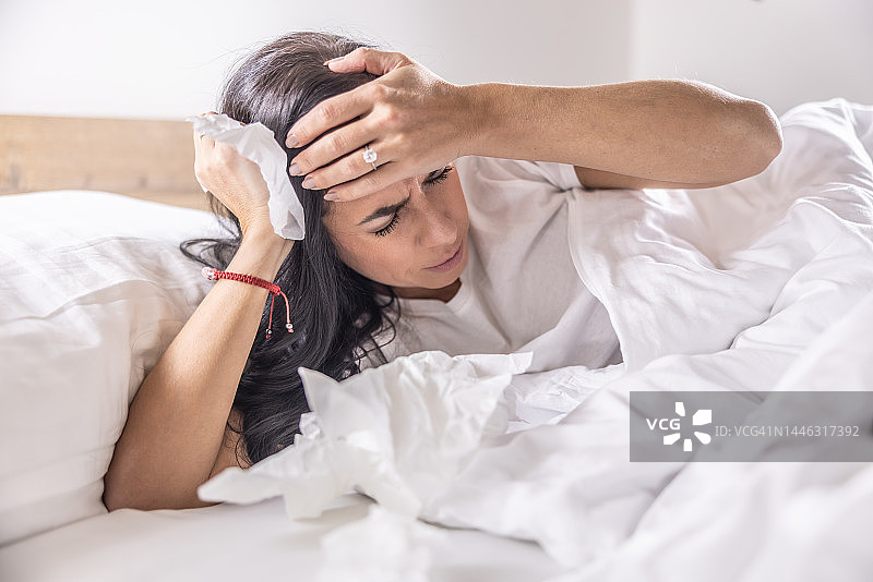 患流感和感冒的病人躺在家里的床上头痛。图片素材