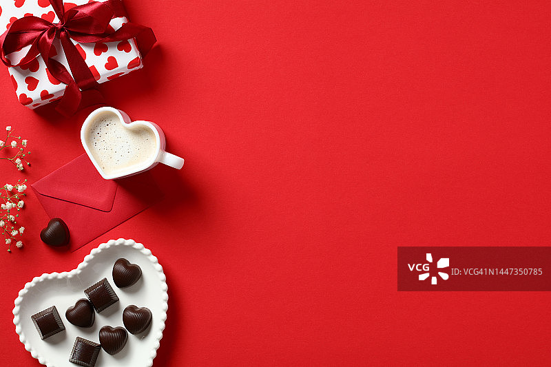 情人节的背景与礼盒，心形糖果，咖啡杯，红信封和鲜花的红色背景。情人节贺卡模板。平铺，俯视图图片素材
