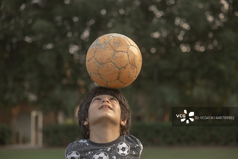 混血儿(印度-伊朗)8岁，踢足球，积极的生活方式。看着镜头微笑图片素材