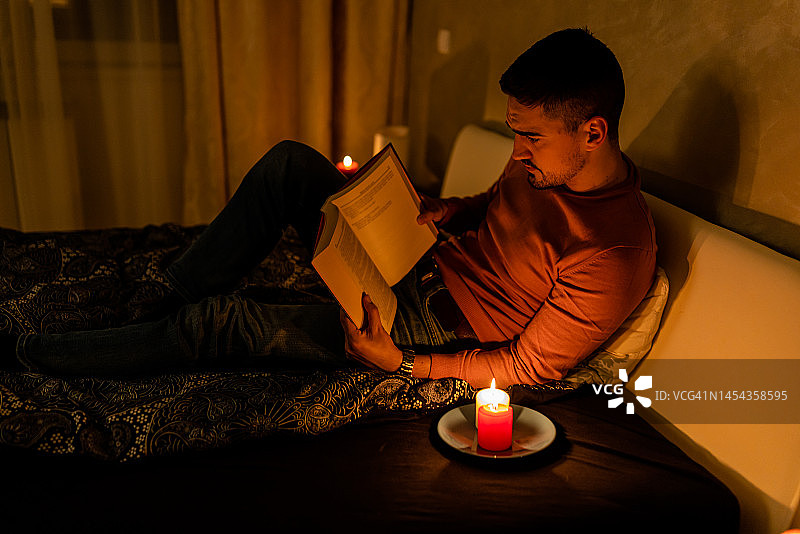 一名男子在精神危机的停电时间看书。图片素材