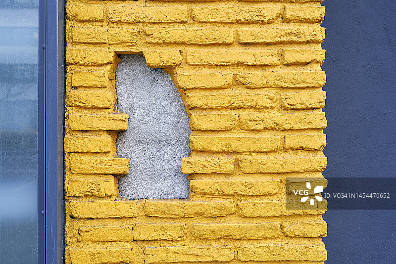 正面视图的砖混凝土墙涂成黄色背景与抽象的洞图片素材