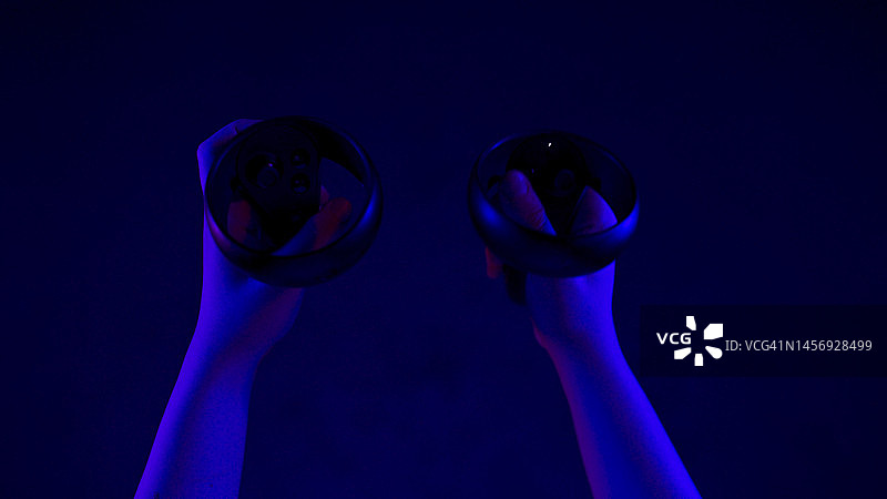 赛博朋克手玩vr闪烁灯光特写。使用控制器的玩家手臂图片素材