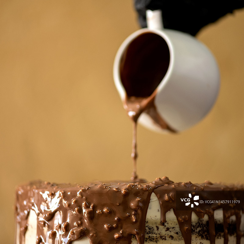 蛋糕上的巧克力糖霜。热巧克力。融化的牛奶巧克力。釉蛋糕。糖衣甜点。巧克力酱碗。烹饪甜食。软的焦点。特写镜头。侧视图。图片素材