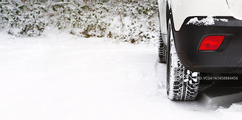汽车用冬季轮胎行驶在积雪覆盖的道路上，冬天的天气，湿滑的街道，危险的驾驶，降雪图片素材