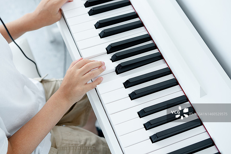 一个小孩的手在白色的电子钢琴上演奏图片素材