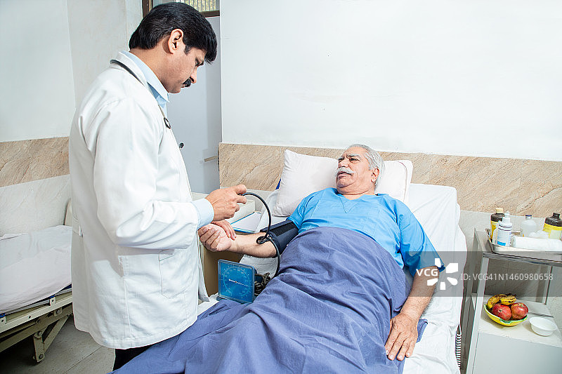 印度医生在诊所或医院测量老年男性病人的高血压。老年人保健理念。图片素材