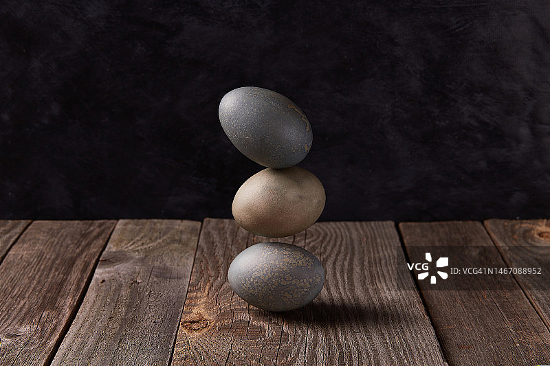 在木桌上平衡染色鸡蛋。复活节庆祝概念图片素材