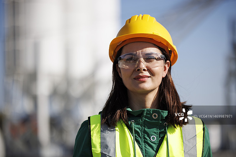 带着安全帽和防护眼镜的微笑女工程师在工厂工作场所图片素材