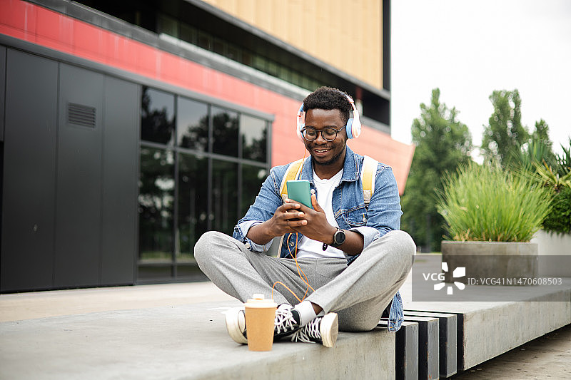 非裔美国学生在街上享受着，用他的智能手机播放音乐图片素材