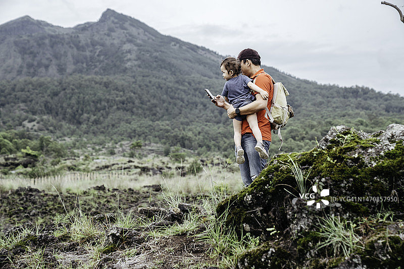 亚洲男子抱着他的孩子看着巴图尔山图片素材