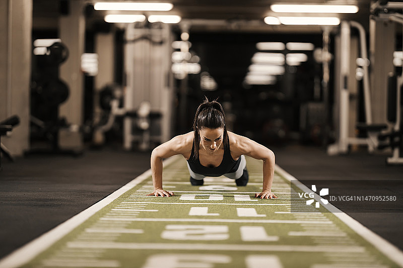 一位强壮的女运动员正在健身房做俯卧撑。图片素材