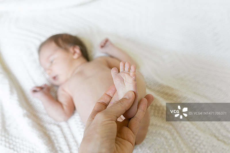 一个成年人抱着一个新生婴儿的脚图片素材