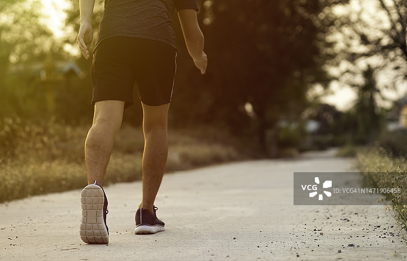 运动员的跑步脚在道路上奔跑，慢跑概念在户外。男人跑步锻炼身体。图片素材