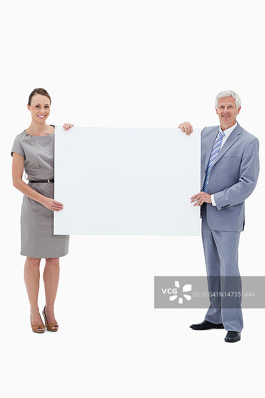 商人微笑着举着一个白色的大牌子和一个女人图片素材