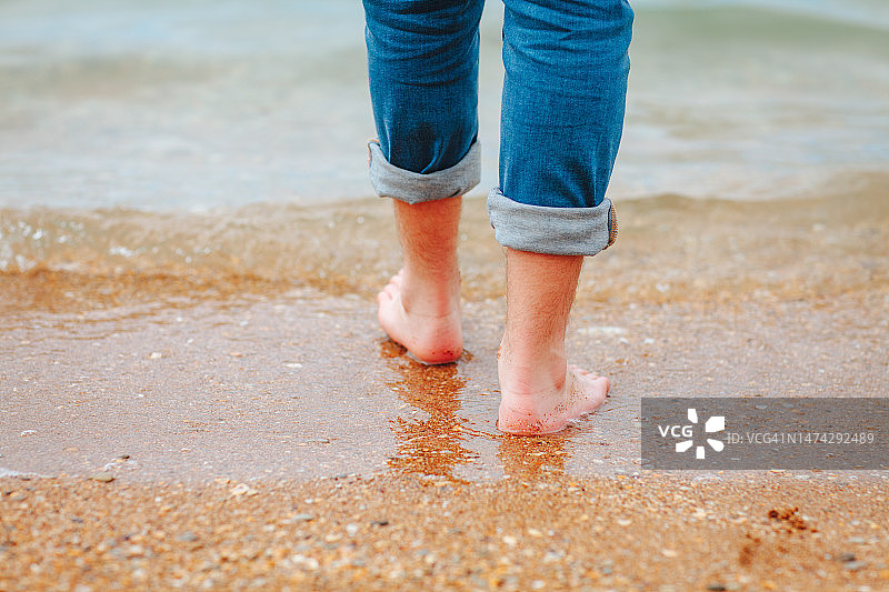 男人的脚踩在大海的沙滩上图片素材