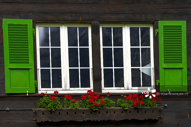 带有彩绘百叶窗和花盆的阿尔卑斯小屋图片素材