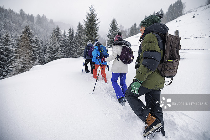在大雪纷飞的冬日，一家人在美丽的山间徒步旅行。图片素材