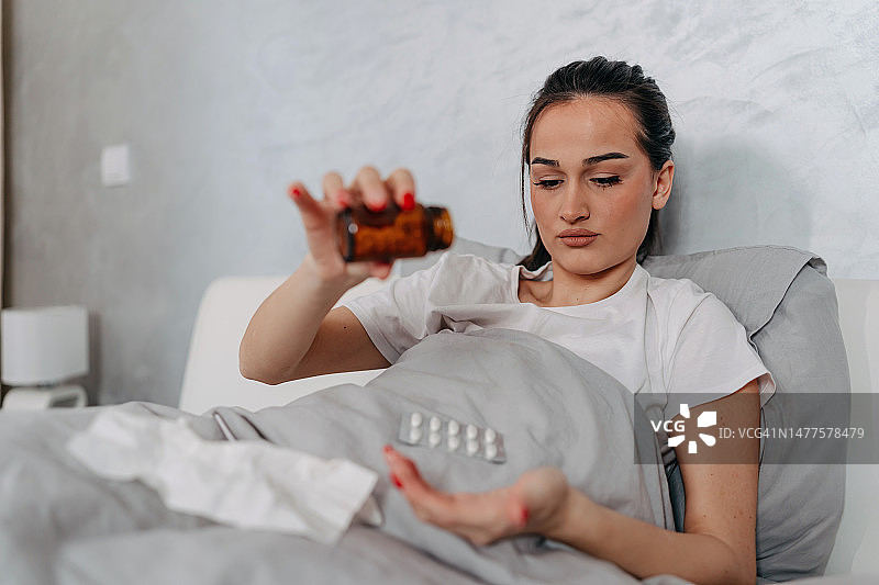 年轻女子在床上吃药图片素材