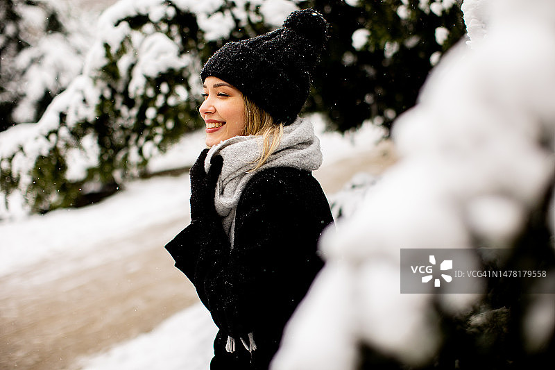 年轻女子在雪中享受温暖的衣服图片素材