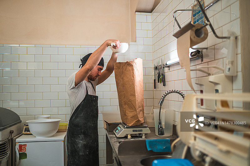 白人面包师在一个小面包房用数字秤称面粉图片素材