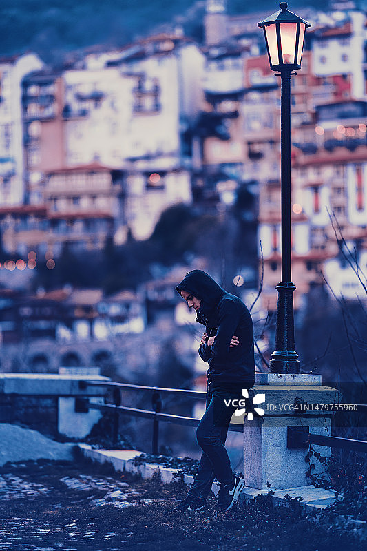 孤独沮丧的年轻人独自站在城市里。图片素材