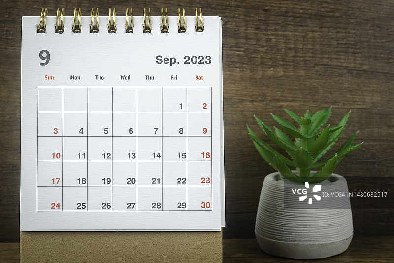 日历桌2023:9月是组织者计划和截止日期的月份，在木质桌子背景上放置室内植物。图片素材