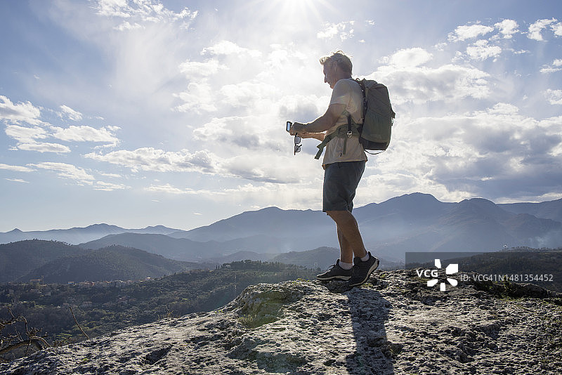 年长的男性徒步旅行者在山顶使用指南针图片素材