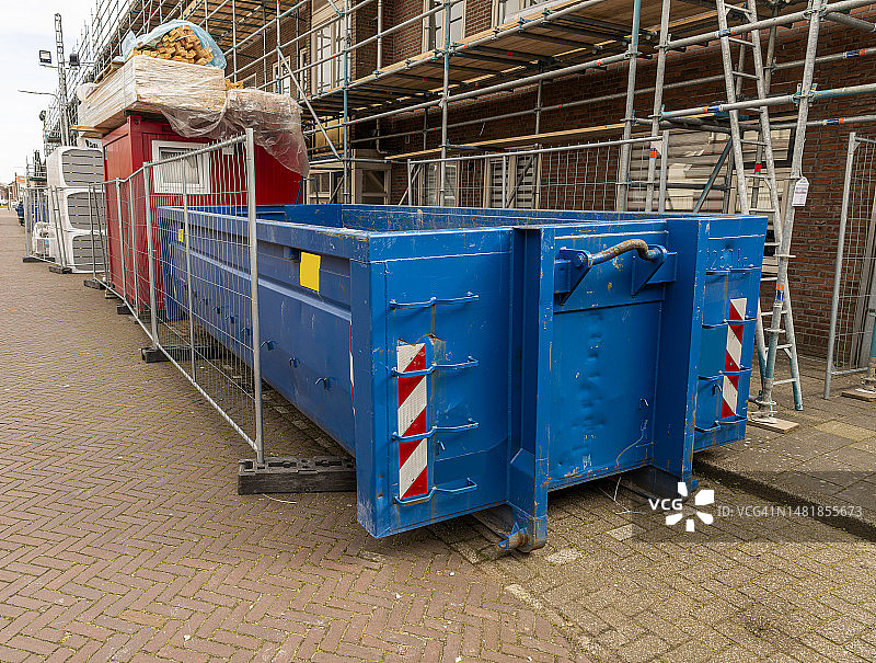 改造区域的细长蓝色开放式钢建筑垃圾容器图片素材