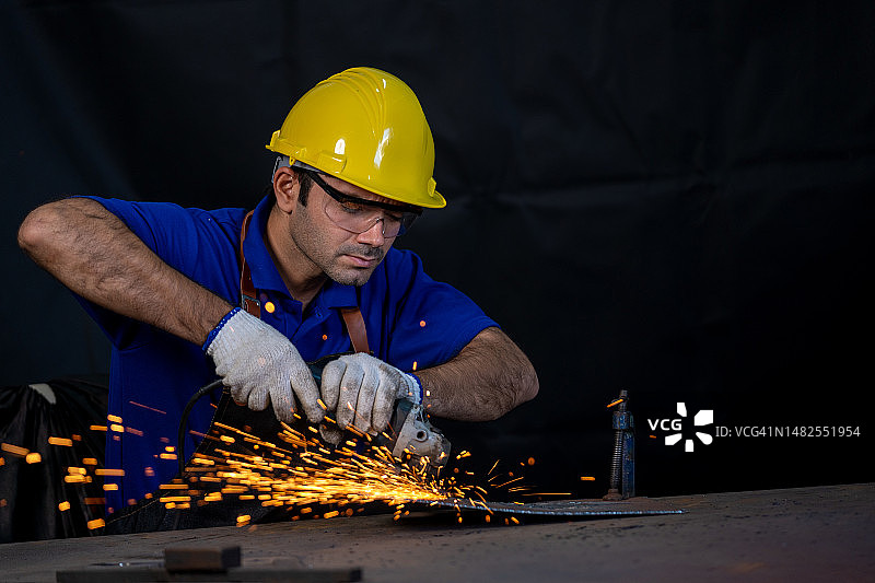金属工人使用角磨床产生大量的火花，专业金属工作使用磨床。图片素材