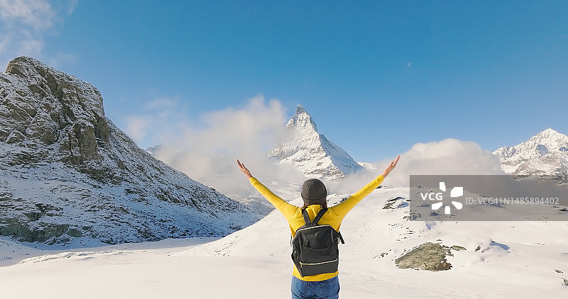 在瑞士马特洪峰山顶上，兴奋的旅行者年轻女子张开双臂。图片素材
