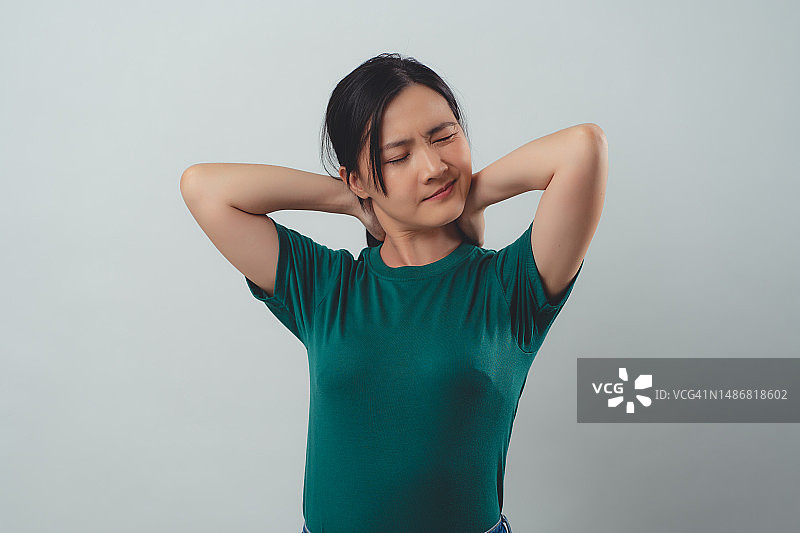 一名亚洲妇女因颈部疼痛而孤立站立。图片素材