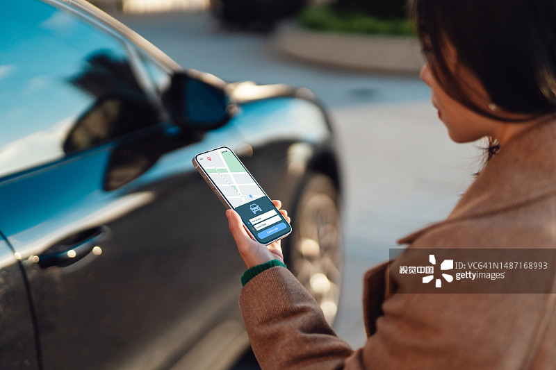 年轻女子在城市中通过智能手机上的移动应用程序预订出租车服务图片素材