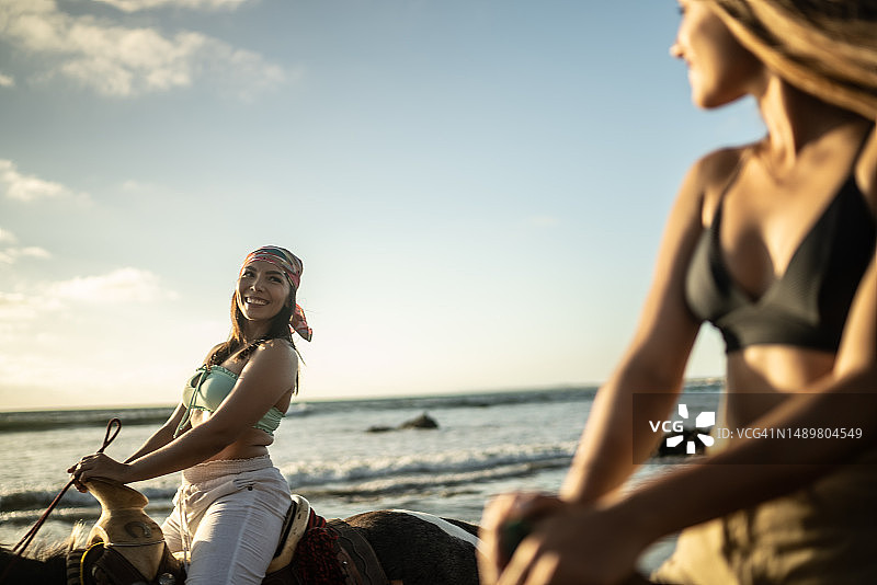 女性朋友在沙滩上骑马图片素材