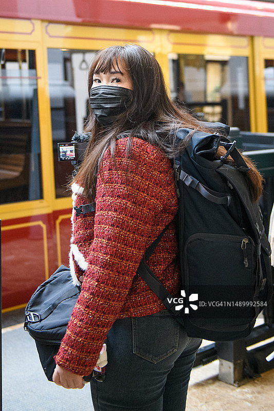 戴着防护口罩等火车的年轻女子在拍视频图片素材