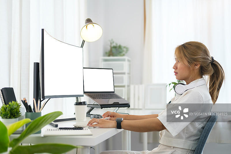 专注的女性软件开发人员在现代办公室的大屏幕上处理程序代码。图片素材