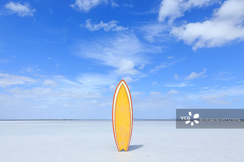 空旷的盐湖上复古的黄色冲浪板。蓝天和拷贝空间。南澳大利亚。图片素材