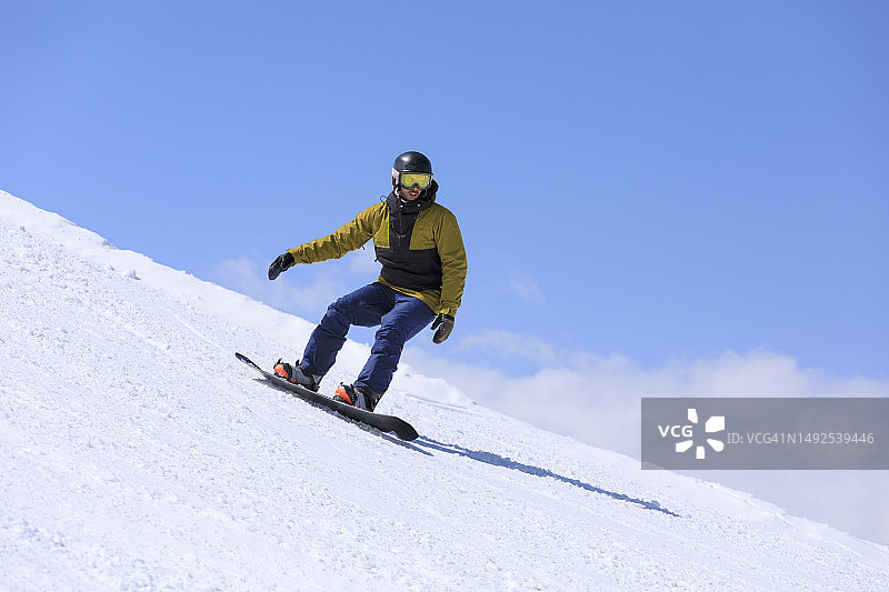 一个年轻人在高山滑雪场上玩单板滑雪图片素材
