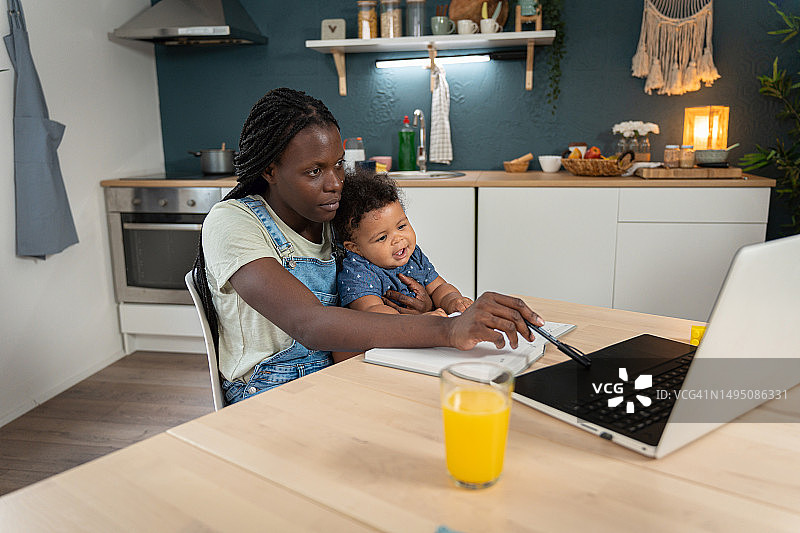 单亲黑人母亲一边照顾她的儿子一边学习电子课程图片素材