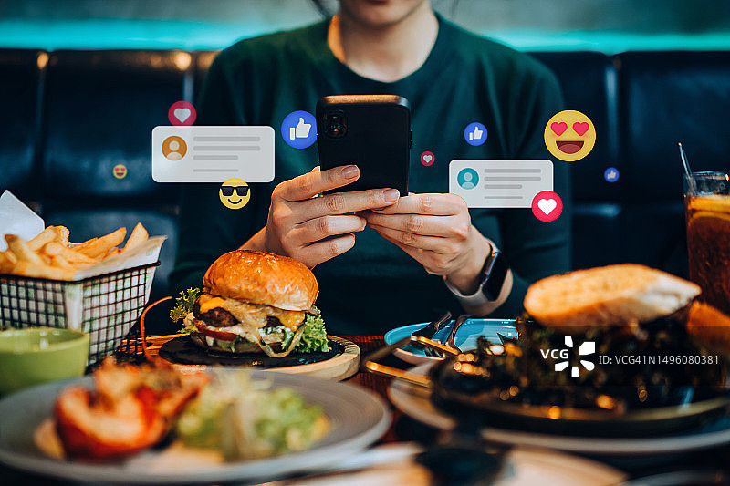 一名年轻亚洲女子在餐厅用餐时在社交媒体应用上使用智能手机的截屏照片。在这个城市的网页上浏览帖子，点赞，爱，评论，交朋友。人们利用技术建立网络。社交媒体成瘾概念图片素材