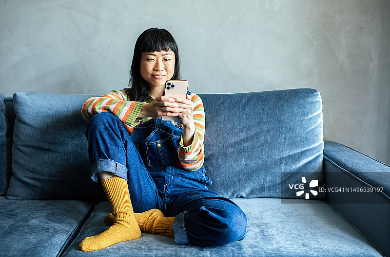 年轻的日本女性在家里使用智能手机图片素材