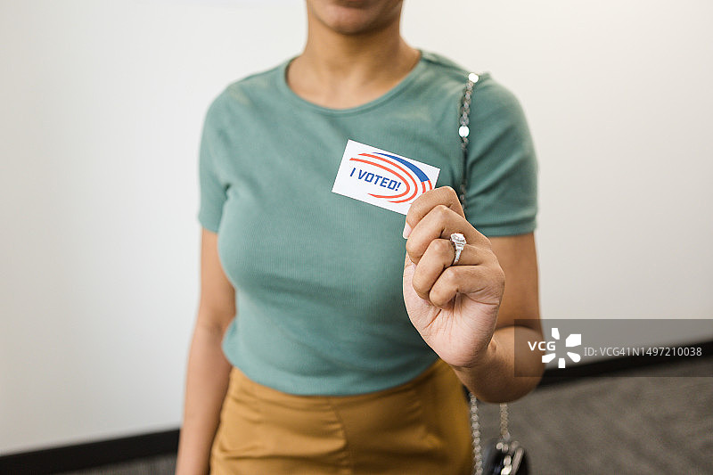 一位无法辨认的女性将她的“我投票了”贴纸靠近镜头图片素材