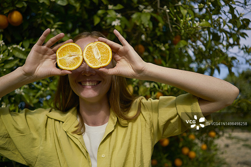 果园里的女人用橘子片蒙住眼睛图片素材