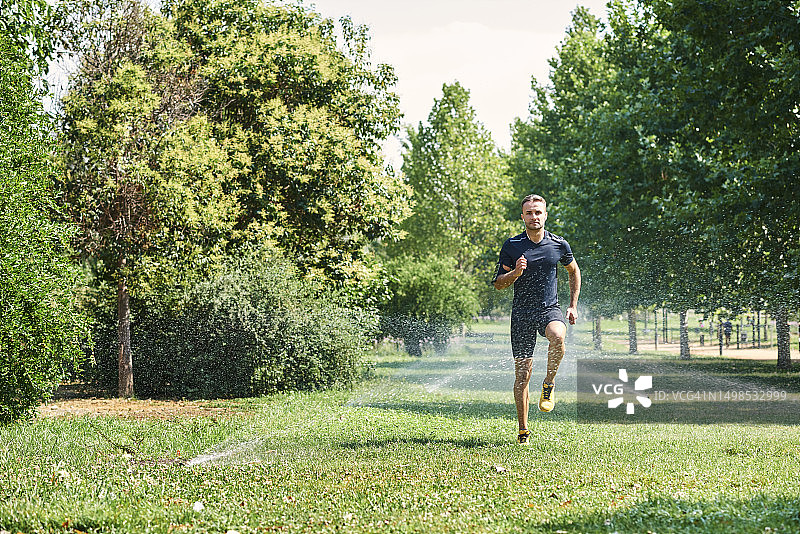 一个年轻人在公园里训练，他正在慢跑图片素材