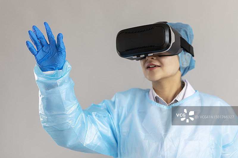 亚洲女医生戴着白色背景的VR耳机。图片素材