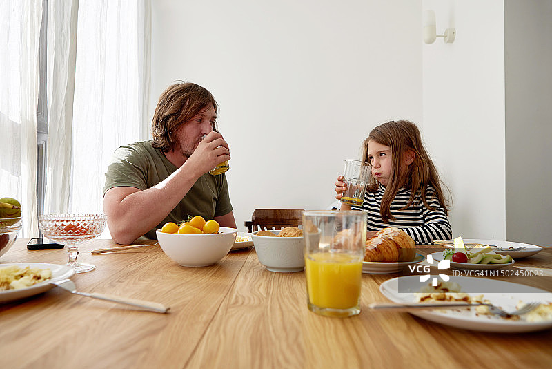 爸爸和女儿在家里吃早餐，看着对方图片素材