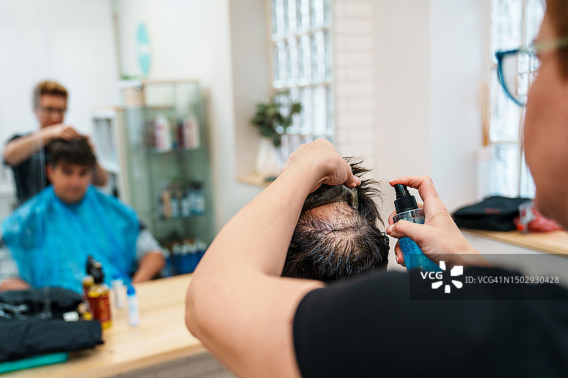 理发师在美发诊所为男士修复和清洁假发图片素材