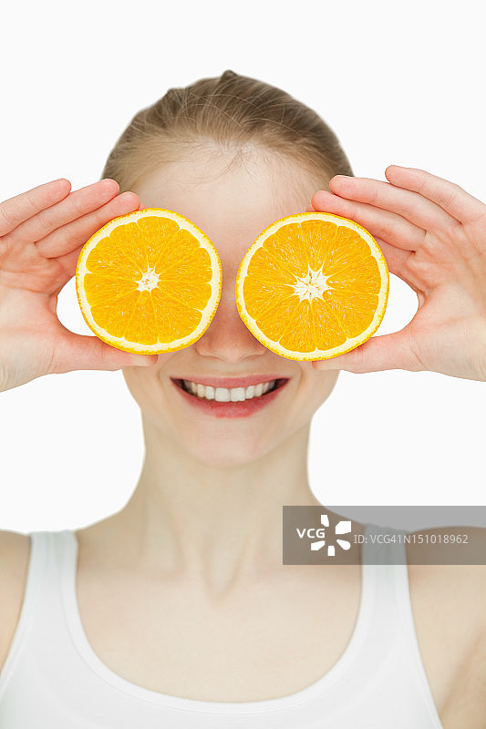 一个女人把橙子放在眼睛上的特写图片素材